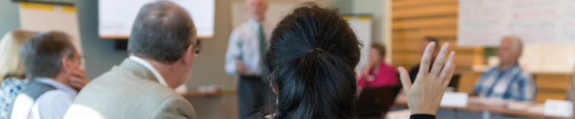 woman raises her hand in a classroom