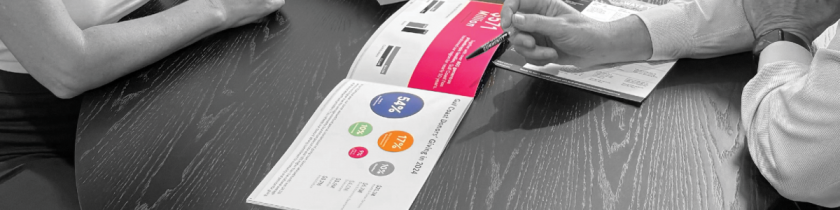 black and white photo except for a circle graph with blue, green, and orange circles and a man holding a pen over the paper