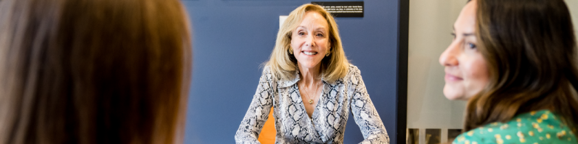woman smiling at two other women across a black table with papers on it