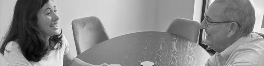 black and white photo of a man and woman looking at each other smiling across a table