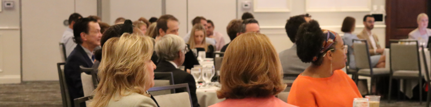 people in a large ballroom look to the front of the room for a presentation
