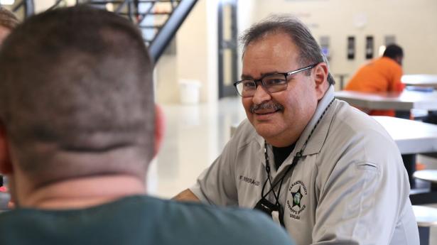 One man from Sarasota County Sheriff's Office smiles at another man inside jail.