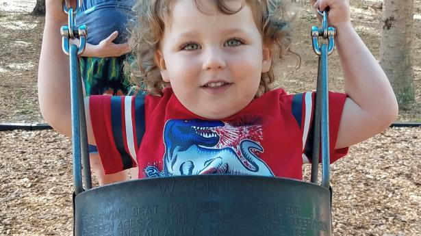 Child in swing smiling.