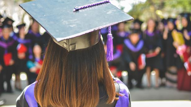 Person standing with graduation cap.