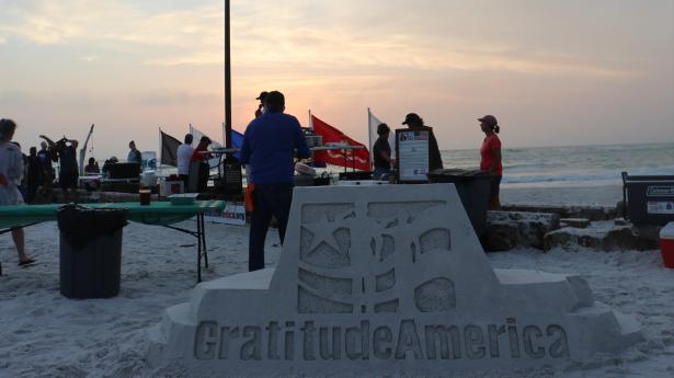 People on beach at retreat with sand sculpture that says: GratitudeAmerica