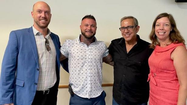 Four people standing, smiling at camera.