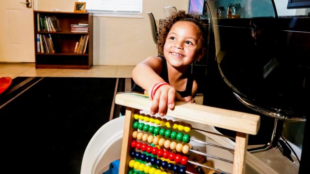Girl smiling, looking at camera with math toy