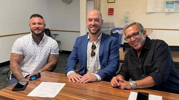 Three men sitting, smiling at camera.