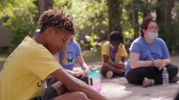 Students sit on ground smiling with water bottles.