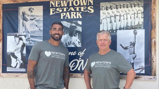 Two men standing, smiling with Newtown Connection t-shirts on.