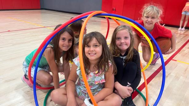 Four children sit around colorful rings smiling.