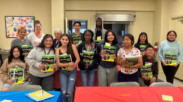 14 students smile at camera holding ACT Prep workbooks. 