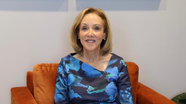 Deb Kabinoff, Gulf Coast Community Foundation's philanthropic friend, sits on orange chair wearing blue dress in Gulf Coast Community Foundation's Sarasota Philanthropy Center.