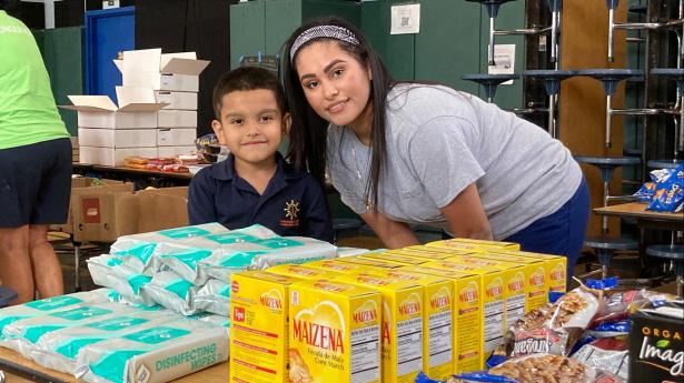 Mom and young son smile at camera with packaged food around them.