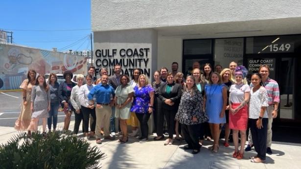About 29 people stand outside of Gulf Coast Community Foundation's Sarasota Philanthropy Center smiling.