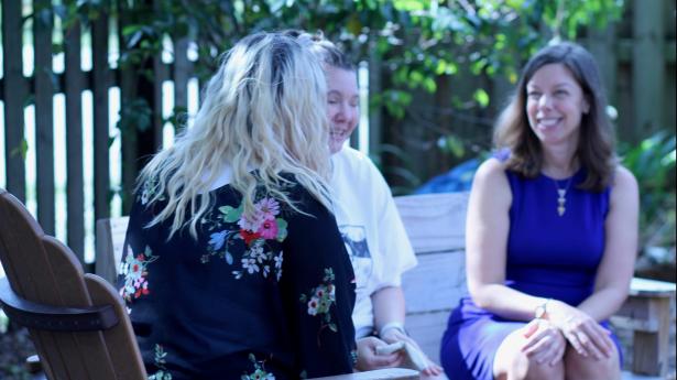Gulf Coast's Director of Community Leadership, Jennifer Johnston, sits outside with two other people smiling.