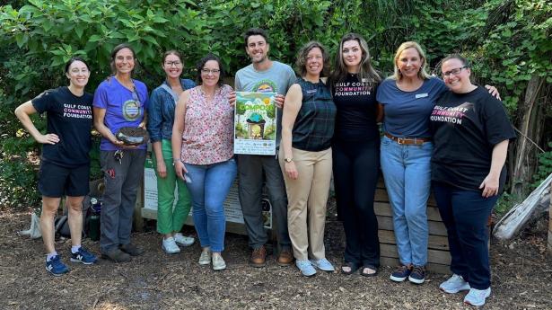 Seven Gulf Coast team members stand smiling outdoors with two people from Sunshine Community Compost.
