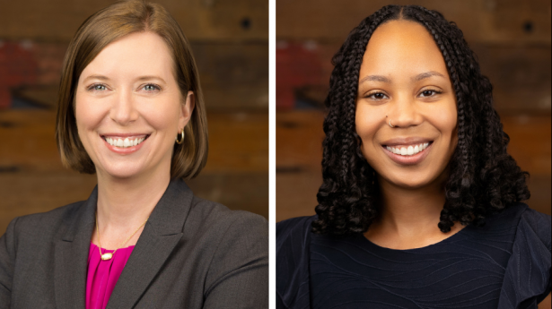 two woman stand smiling at the camera against a wood wall
