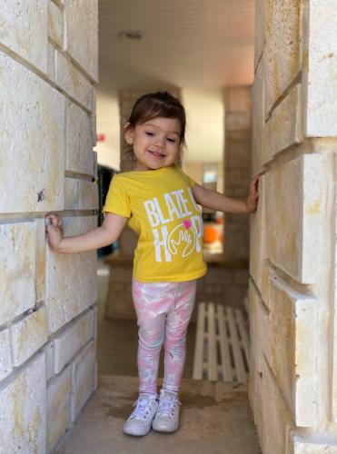 Young girl stands in wall and smiles.