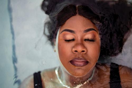 Photograph of woman closing her eyes with water all around her.