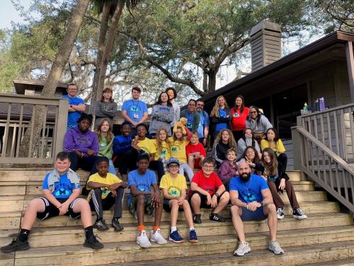 Over 15 students from Camp Mariposa sit on balcony outdoors.