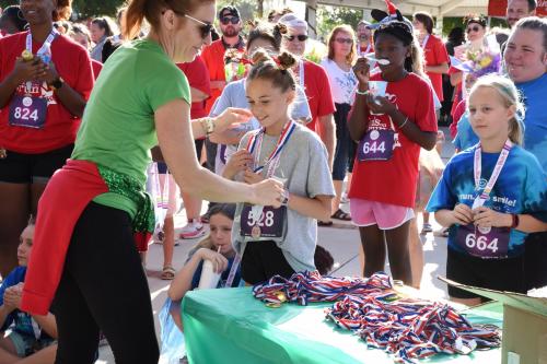 Young girl accepts medal at race. Many youth are behind her.