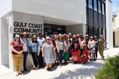 About 25 people stand outside of Gulf Coast's Sarasota Philanthropy Center with fun hats on.