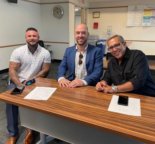 Three men sitting, smiling at camera.