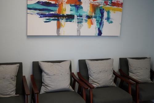 Four chairs in an office, painting on wall.