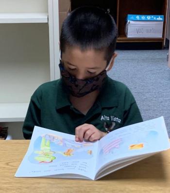 child reading with mask on